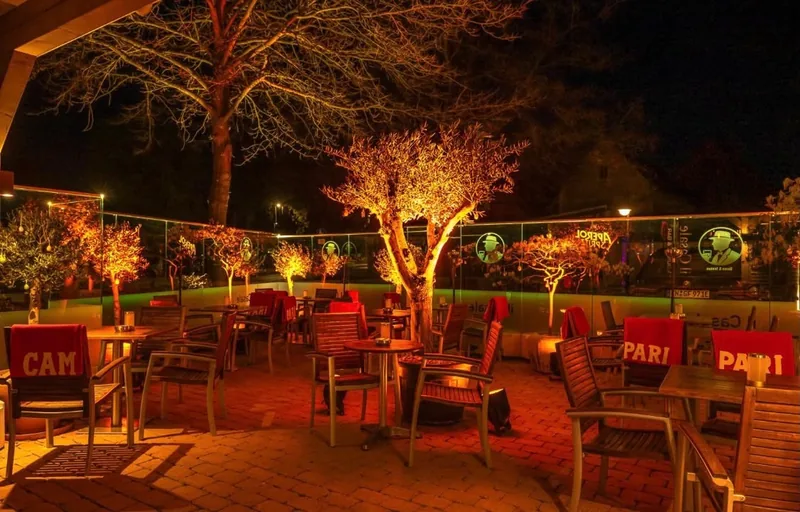 Terrasse der il Casale Lounge & Bar am Abend mit beleuchteten Bäumen und Glaswand
